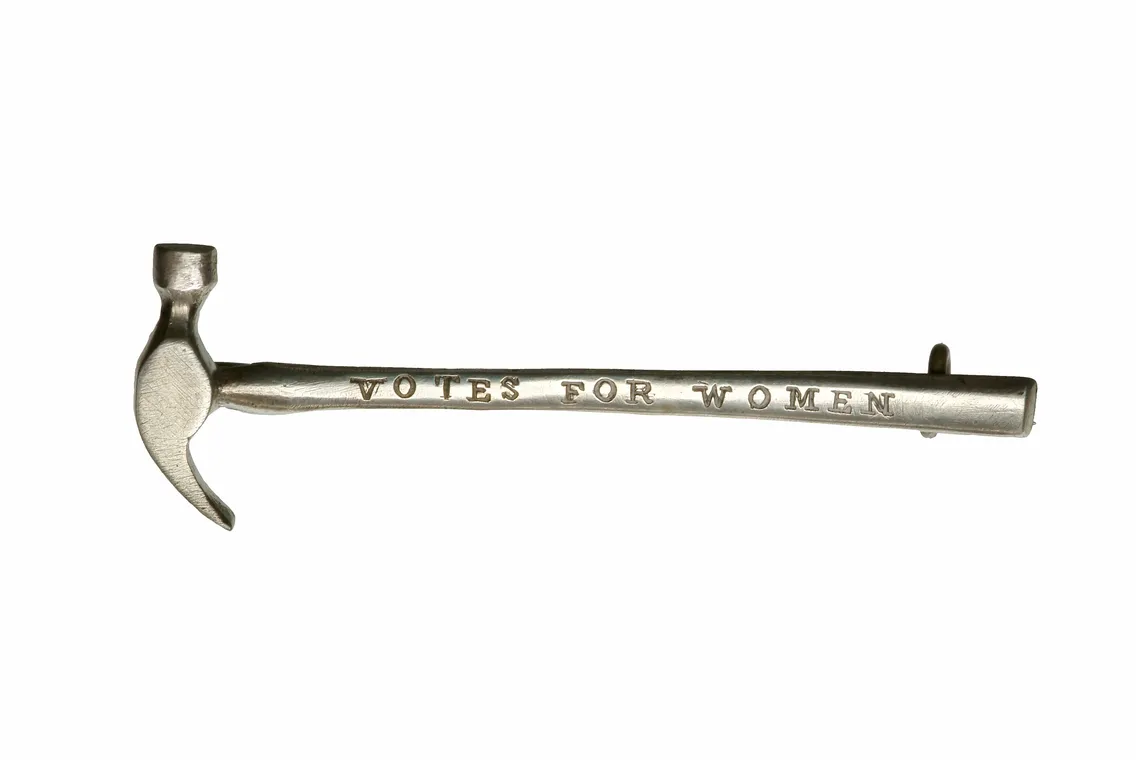 A silver hammer with the inscription "votes for women" on its handle, isolated on a white background.