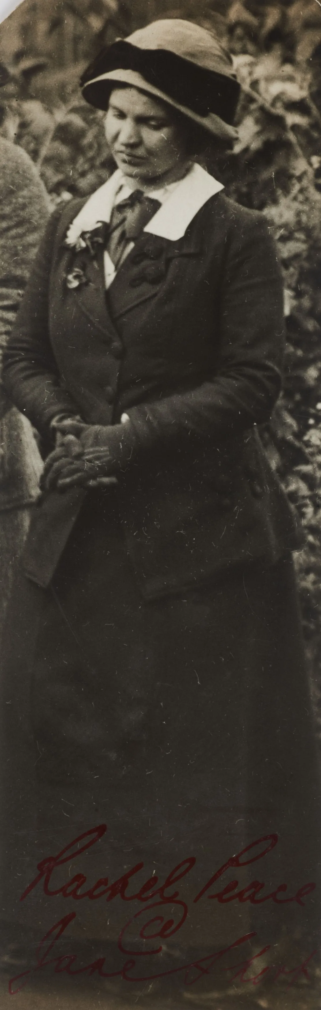 Vintage black-and-white photo of a woman in a cloche hat and coat, standing outdoors with a slight smile, signed "loving peace and joy.