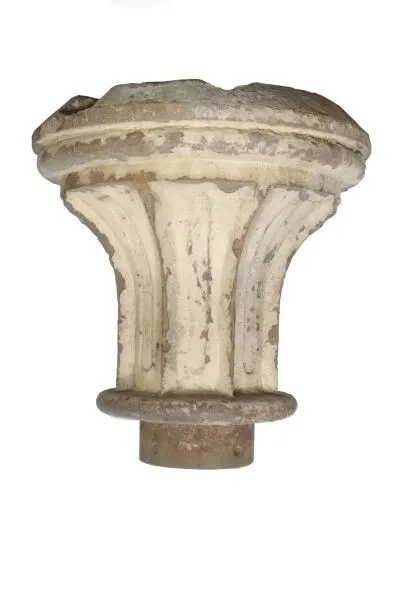 Ancient stone capital with intricate carvings, showing signs of wear, isolated on a white background.