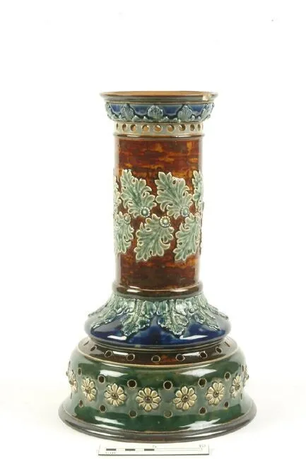An ornate ceramic candle holder with a detailed floral design in green and blue colors, displayed on a white background.