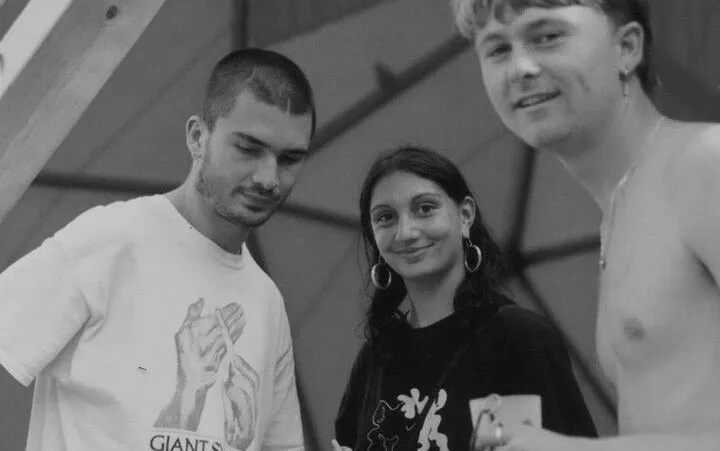 A black and white photograph of three people smiling to camera