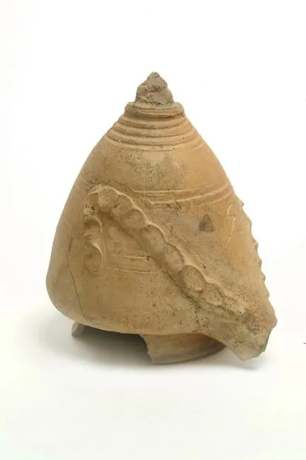 Ancient broken pottery shard with spiral and dotted designs on a plain background.
