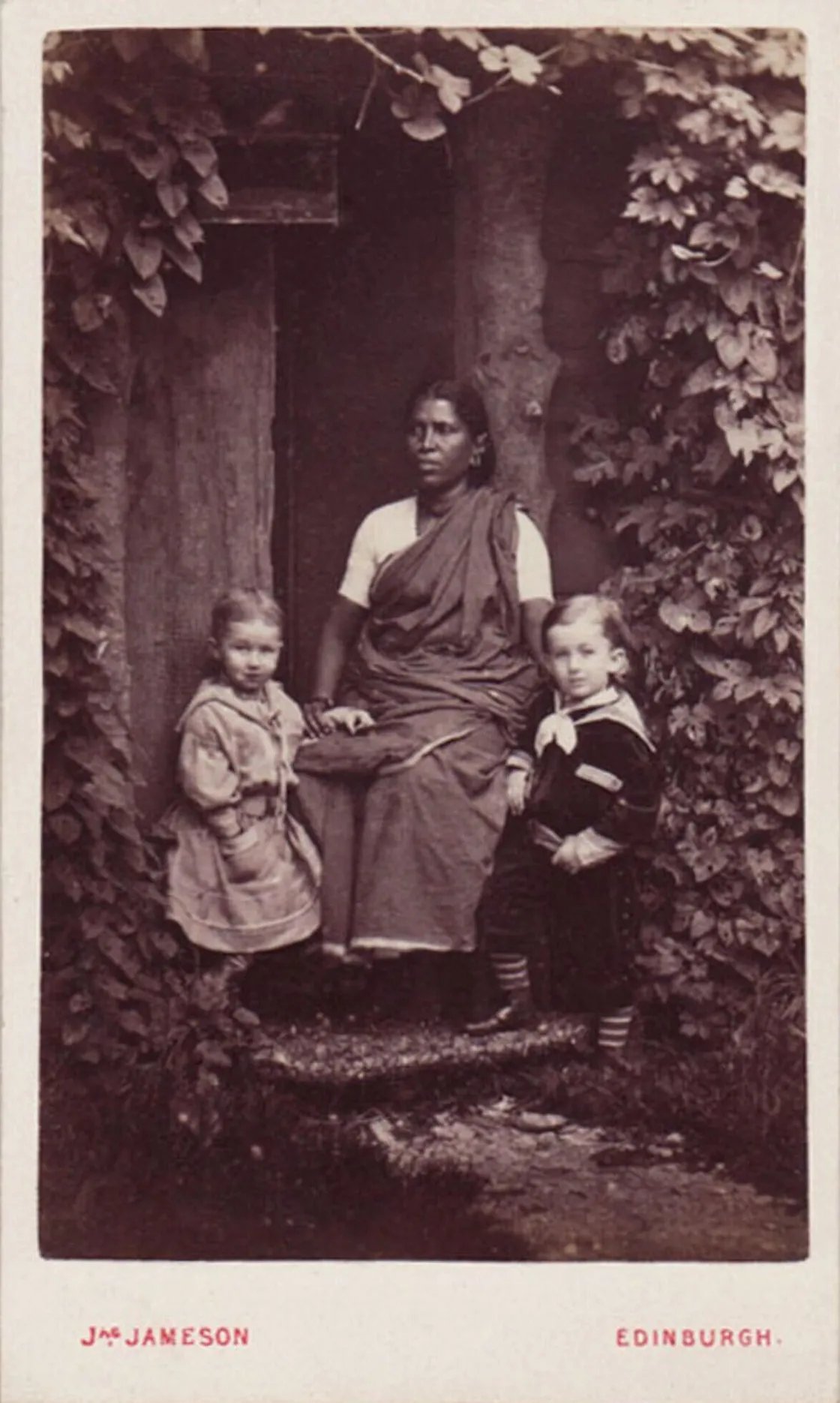 Two small children and an older woman sat on the stairs of a building