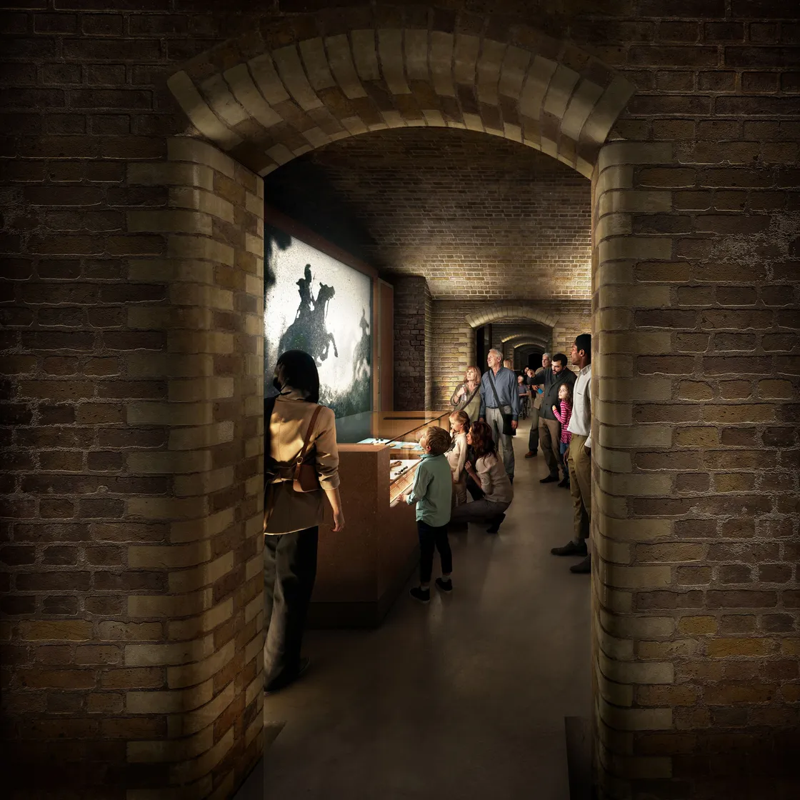 People view exhibits in a brick hallway with arched vaults at a museum; some read displays while others watch a large CGI-projected image on the wall.