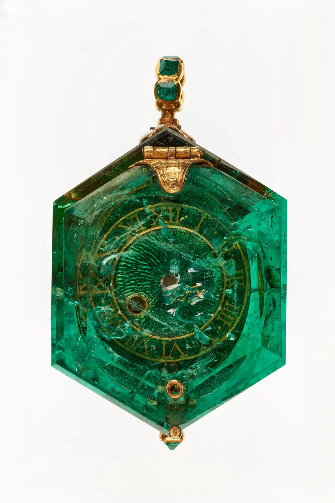 An intricately carved emerald watch with gold accents, featuring Roman numerals and central geometric patterns.