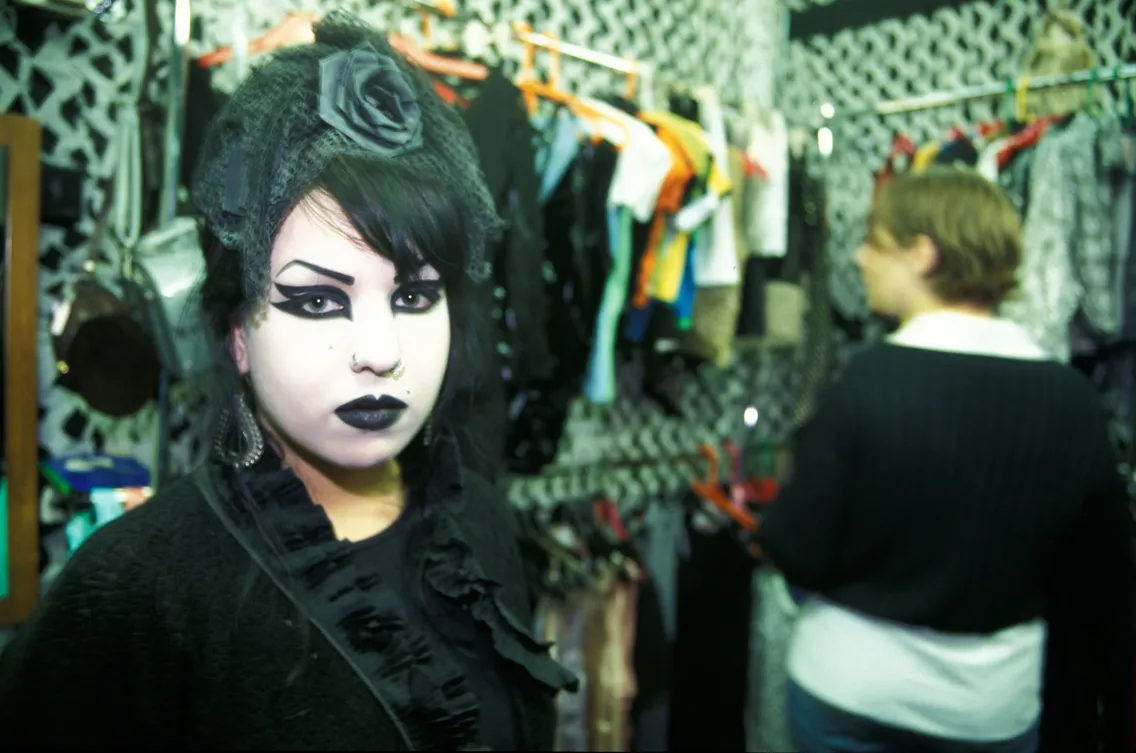 A black-haired woman looking towards the camera wearing heavy, goth-style make-up
