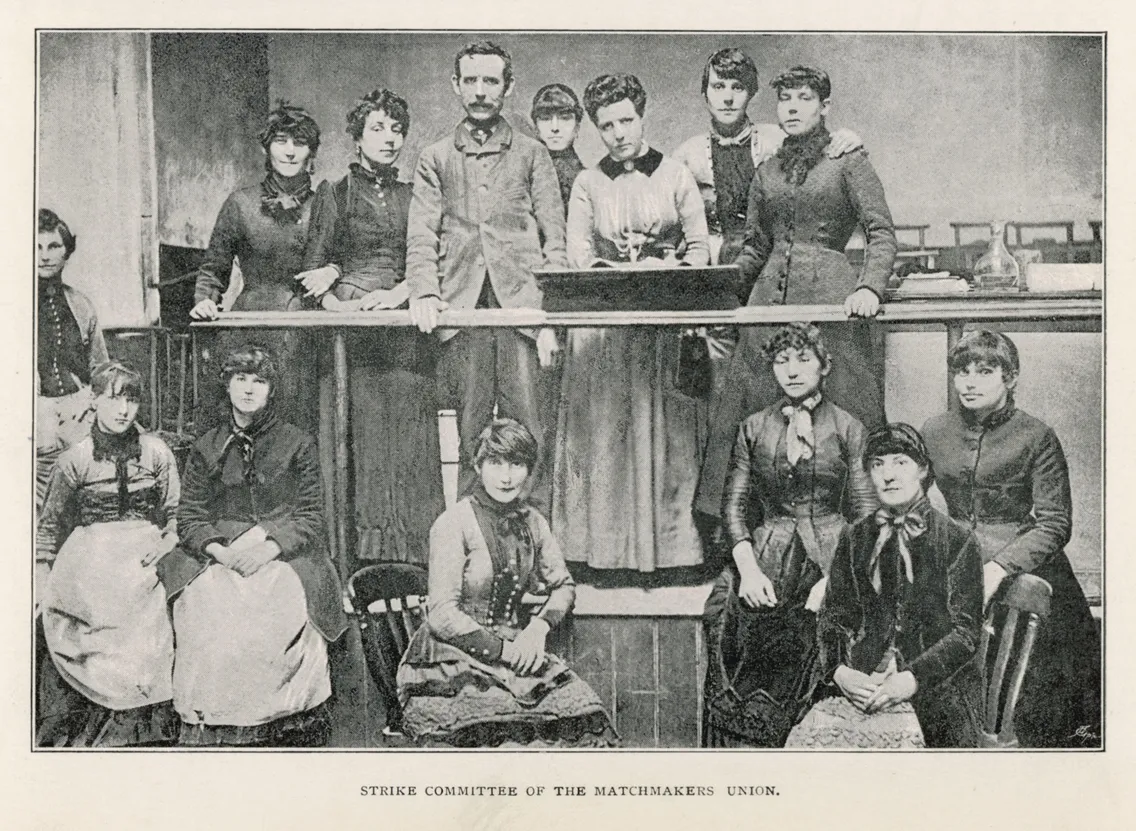 Black and white photo of thirteen people, mostly women, posing in two rows around a table. Caption reads: “Strike Committee of the Matchmakers’ Union.” Likely showing members of the committee formed during Besant’s involvement in the historic Match s