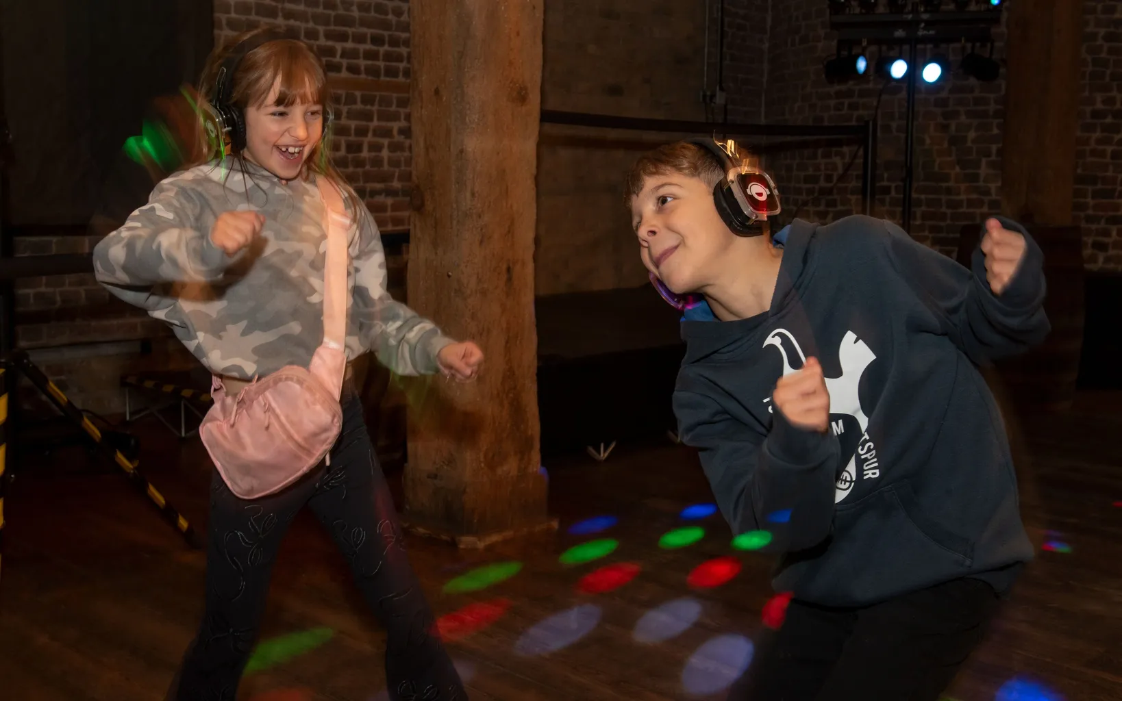 Two children dance whilst wearing headphones.