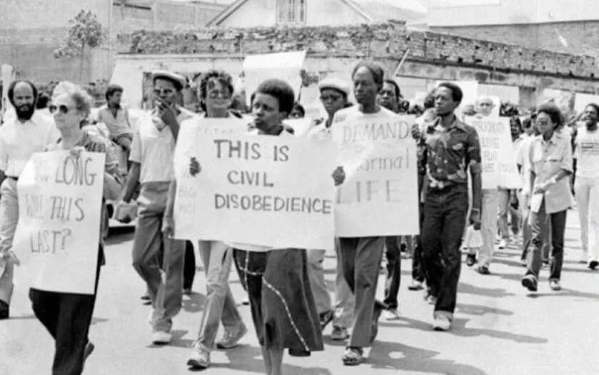 Black and white historic photograph of people marching with banner stating 'This is civil disobedience'