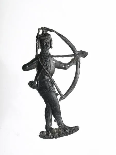 A small, antique bronze statue of a figure holding a large bow, with detailed attire and accessories, set against a plain white background.