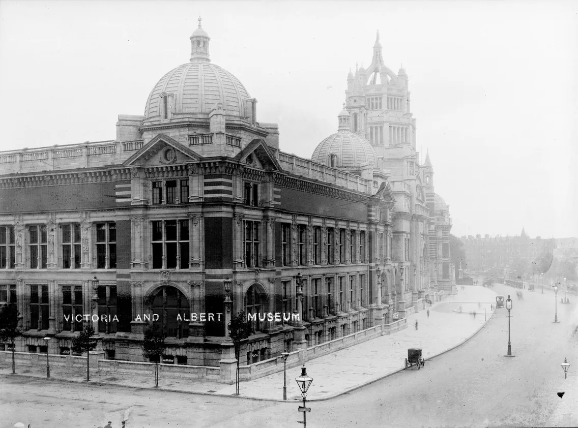 Historical black and white photo of the victoria and albert museum in london, showing its grand facade and empty street.