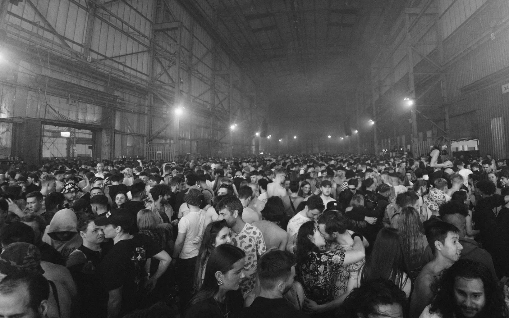 A black and white image of a large crowd of people in a long, open space