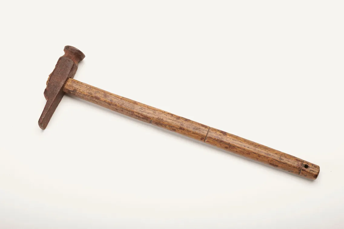 A vintage hammer with a wooden handle and a rusted metal head, photographed on a white background.