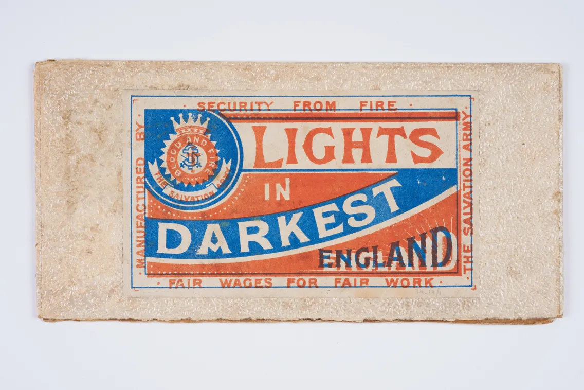 A vintage matchbox label reads "Lights in Darkest England," with Salvation Army emblems and text promoting security, fire safety, and fair wages.