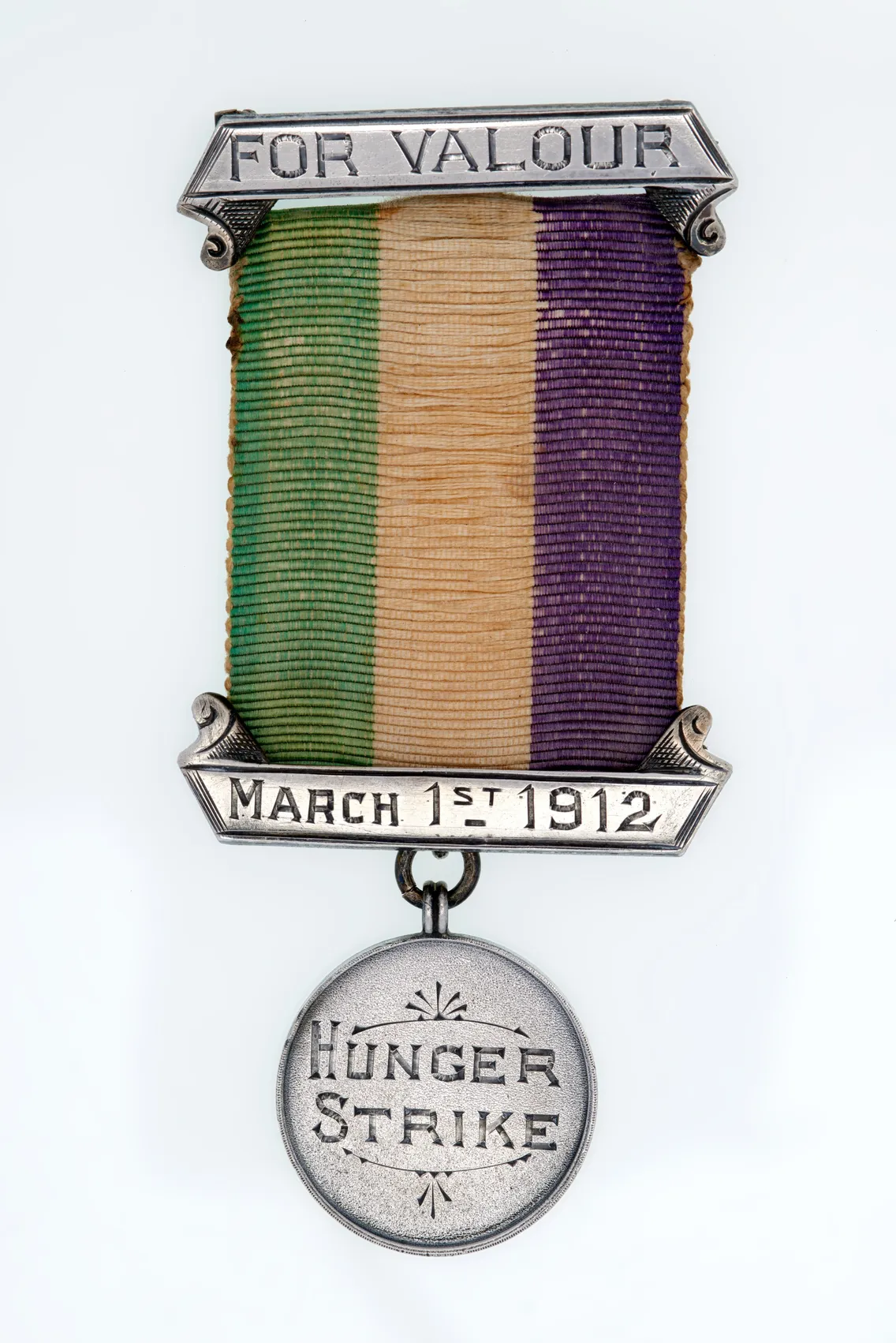 A silver medal with a tri-color ribbon and the inscriptions "FOR VALOUR," "MARCH 1ST 1912," and "HUNGER STRIKE" engraved on its parts.