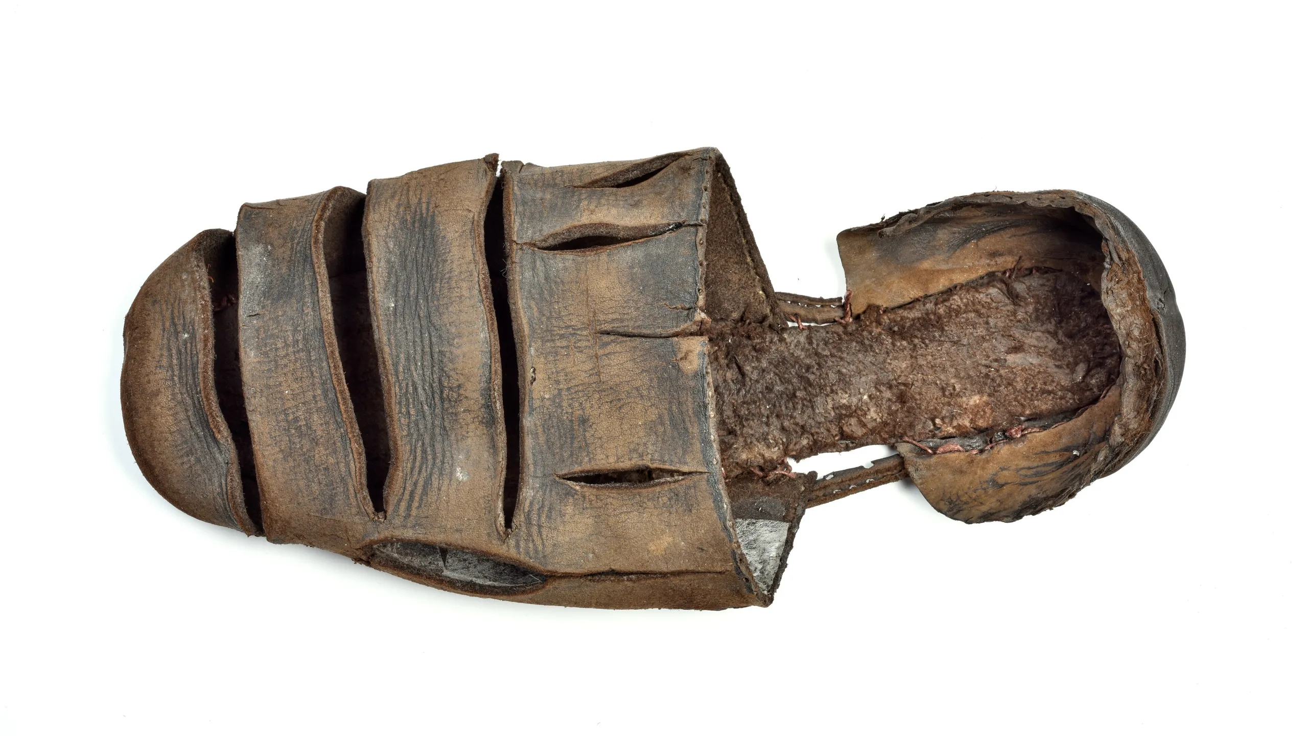 Leather shoe with single, narrow sole, square toe and three large horizontal slashes on foot, with smaller vertical slashes close to instep. Back heel [?] separate from toe [?], [?] cut and stitching around upper-edge suggests it is incomplete.