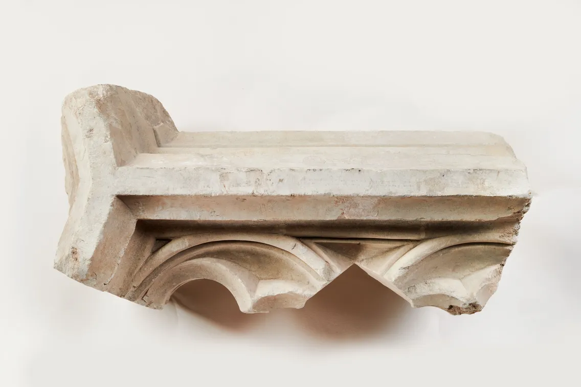 A carved stone architectural fragment with two pointed arches and delicate tracery, resembling a window, displayed against a plain white background.
